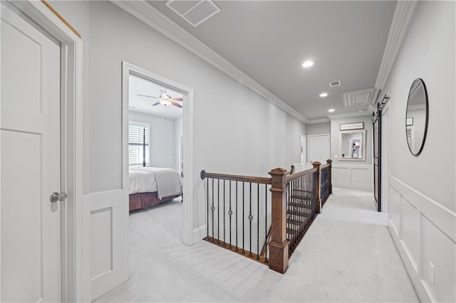 corridor featuring light colored carpet, crown molding, an upstairs landing, a decorative wall, and recessed lighting