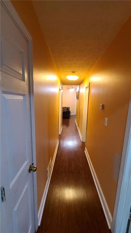 hall with dark wood-style flooring and baseboards