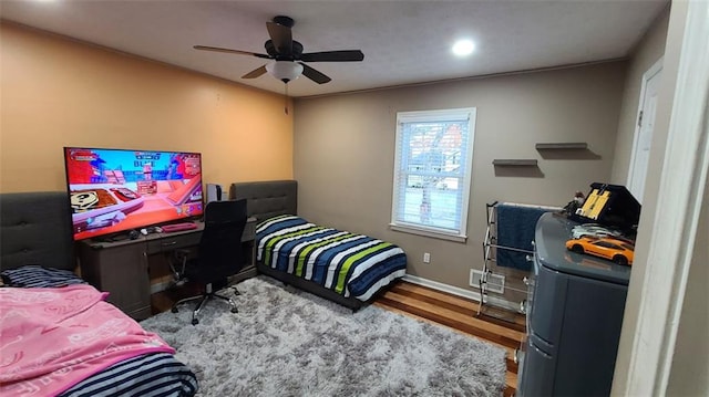 bedroom featuring washer / dryer, ceiling fan, baseboards, and wood finished floors