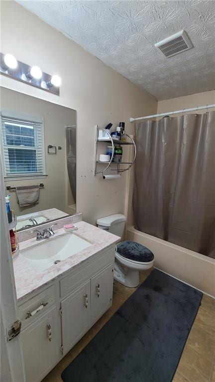 full bath with shower / tub combo with curtain, visible vents, toilet, vanity, and a textured ceiling