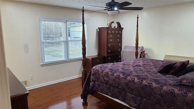 bedroom featuring ceiling fan, wood finished floors, visible vents, and baseboards