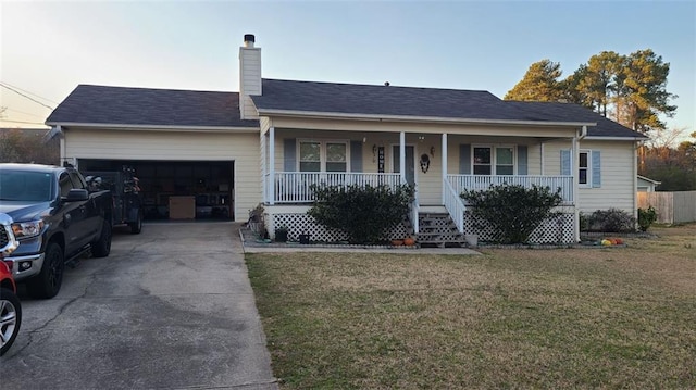 ranch-style home with a chimney, a porch, an attached garage, driveway, and a front lawn