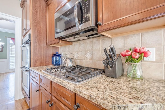 1765 Dew Pl, Marietta, GA 30064 - kitchen with appliances with stainless steel finishes, crown molding, backsplash, brown cabinets, and light stone countertops