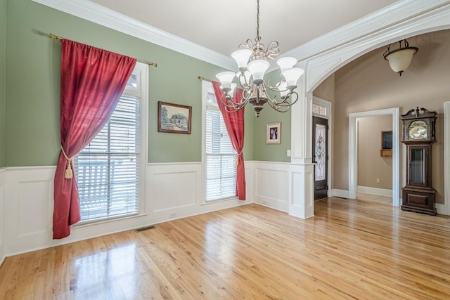 1765 Dew Pl, Marietta, GA 30064 - unfurnished dining area featuring arched walkways, a chandelier, wainscoting, light wood finished floors, and ornamental molding