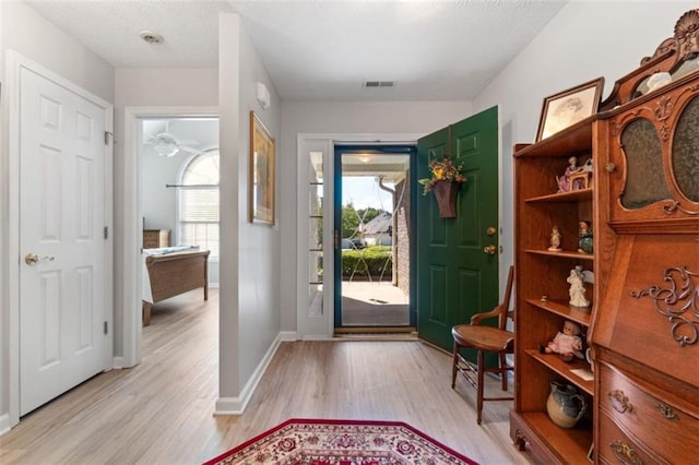 foyer entrance featuring a wealth of natural light, visible vents, baseboards, and light wood-style floors