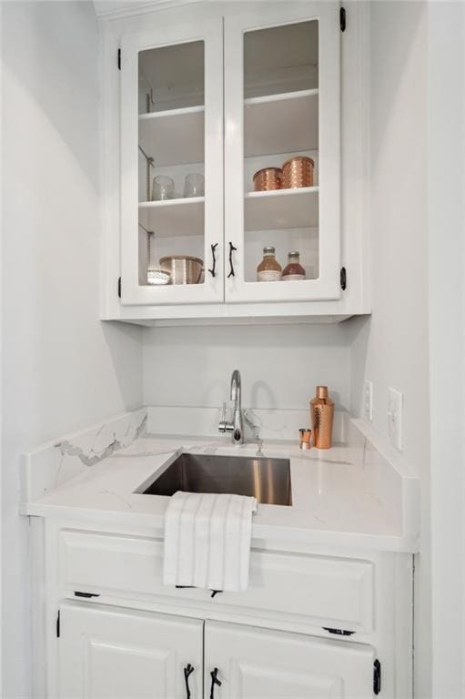 kitchen with tasteful backsplash, sink, white cabinetry, light wood-type flooring, and stainless steel appliances