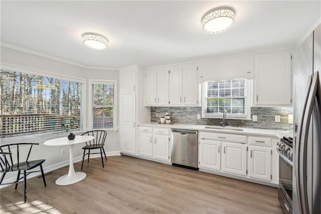 kitchen with backsplash, sink, light hardwood / wood-style flooring, appliances with stainless steel finishes, and white cabinets