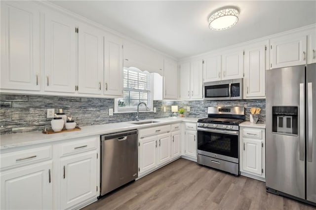 kitchen with light hardwood / wood-style floors, decorative backsplash, crown molding, appliances with stainless steel finishes, and white cabinets