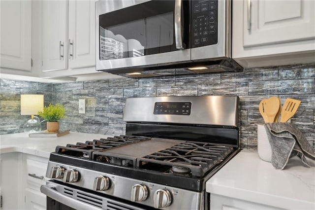 kitchen with backsplash, light hardwood / wood-style floors, stainless steel dishwasher, white cabinetry, and ornamental molding