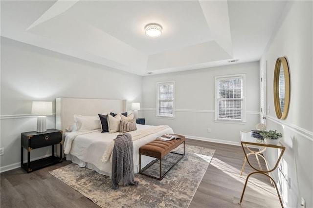 bedroom with hardwood / wood-style floors and a tray ceiling