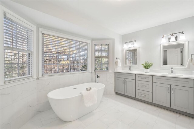 bathroom featuring a bathing tub, tile walls, and vanity