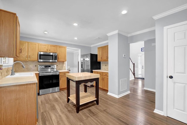 kitchen with stainless steel appliances, a sink, backsplash, light wood-style floors, and light countertops
