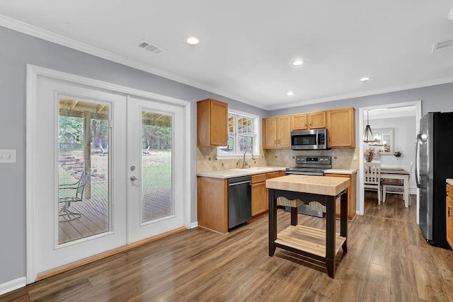 kitchen featuring appliances with stainless steel finishes, french doors, light countertops, wood finished floors, and tasteful backsplash