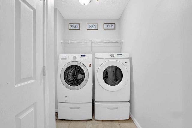 laundry room featuring washer and dryer, light tile patterned floors, a textured ceiling, and baseboards