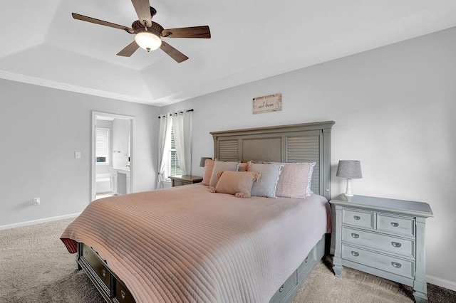 bedroom featuring light carpet, a tray ceiling, baseboards, ceiling fan, and connected bathroom