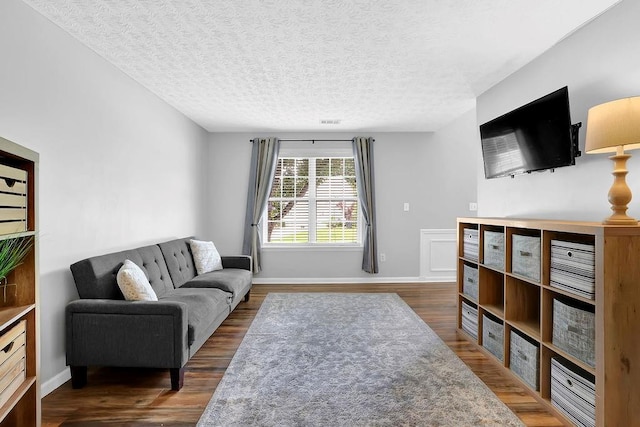 living room featuring dark wood finished floors, baseboards, and a textured ceiling