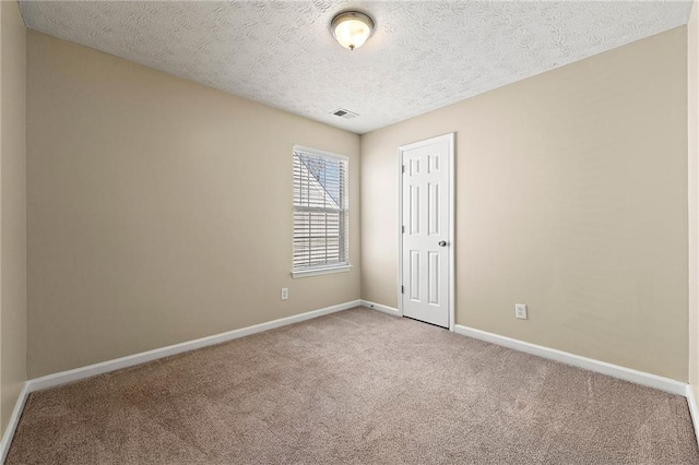 empty room with baseboards, visible vents, a textured ceiling, and light colored carpet