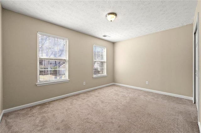 unfurnished room with carpet, visible vents, baseboards, and a textured ceiling