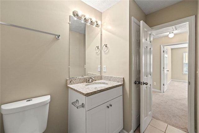 half bathroom with baseboards, vanity, toilet, and a textured ceiling