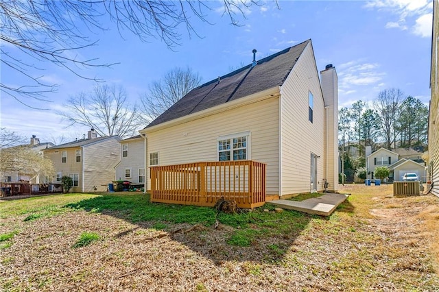 rear view of property featuring a chimney, a residential view, a deck, and a yard