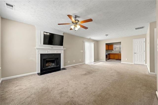 unfurnished living room featuring a fireplace with flush hearth, visible vents, baseboards, and light colored carpet