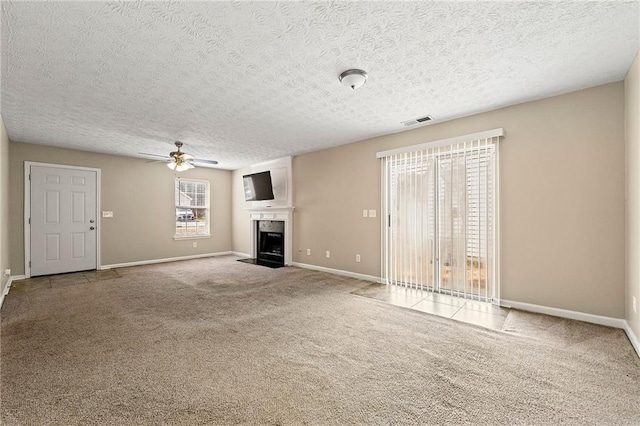 unfurnished living room featuring carpet, visible vents, ceiling fan, and a fireplace with flush hearth