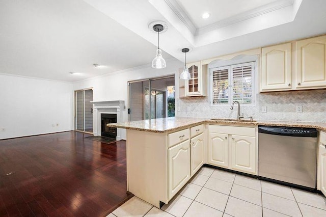 kitchen with hanging light fixtures, stainless steel dishwasher, a tray ceiling, ornamental molding, and sink