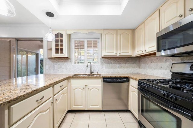 kitchen featuring appliances with stainless steel finishes, hanging light fixtures, light stone counters, ornamental molding, and sink