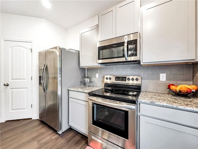 kitchen featuring white cabinetry, appliances with stainless steel finishes, dark hardwood / wood-style floors, light stone countertops, and backsplash