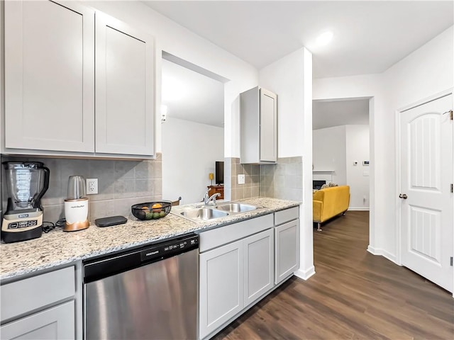 kitchen with sink, backsplash, light stone countertops, dark hardwood / wood-style flooring, and stainless steel dishwasher