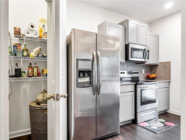 kitchen featuring tasteful backsplash, appliances with stainless steel finishes, dark hardwood / wood-style floors, and gray cabinetry