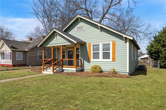 bungalow with central air condition unit, covered porch, a front lawn, and fence