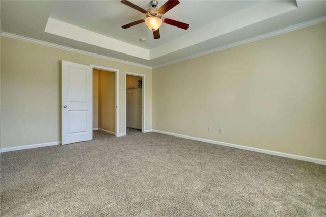 unfurnished bedroom with carpet, crown molding, a raised ceiling, a ceiling fan, and baseboards