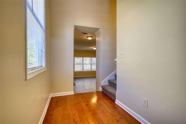 hall featuring visible vents, stairway, baseboards, and wood finished floors