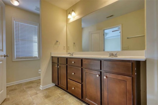 bathroom with double vanity, baseboards, visible vents, and a sink