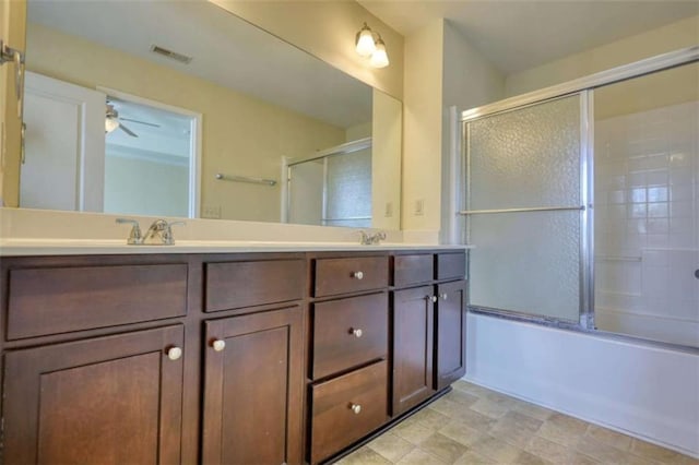 full bathroom with visible vents, a sink, combined bath / shower with glass door, and double vanity