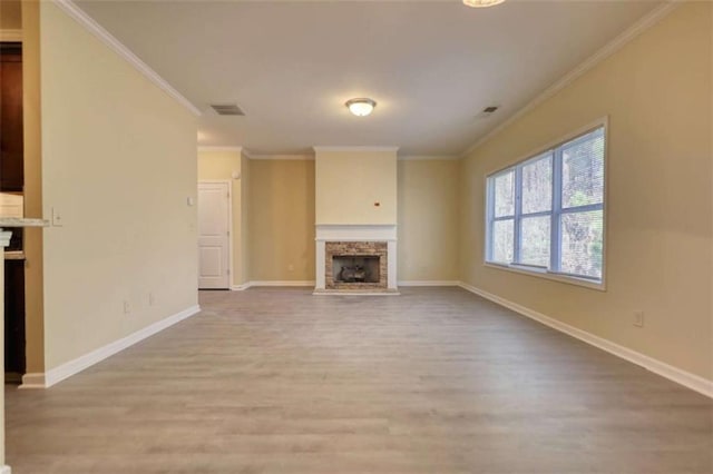 unfurnished living room with light wood-style flooring, a fireplace, ornamental molding, and baseboards