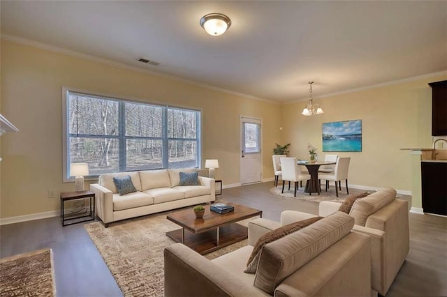 living area with baseboards, visible vents, a chandelier, and ornamental molding