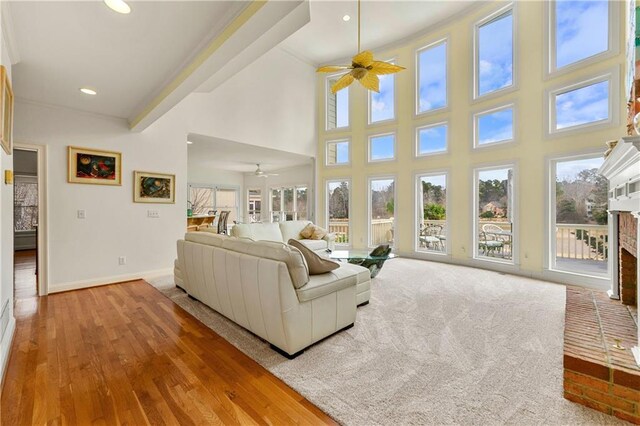 living area featuring recessed lighting, a towering ceiling, a brick fireplace, ceiling fan, and baseboards