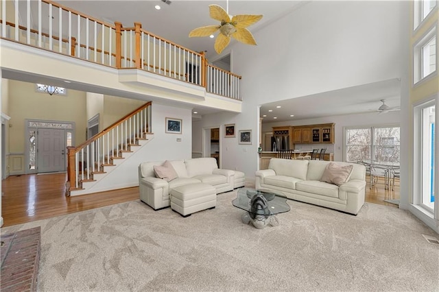 living area featuring light wood-style flooring, a high ceiling, and stairway