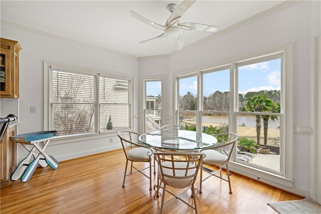 dining room featuring ornamental molding, light wood finished floors, plenty of natural light, and baseboards