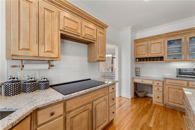 kitchen with built in study area, glass insert cabinets, black electric stovetop, crown molding, and light wood-type flooring