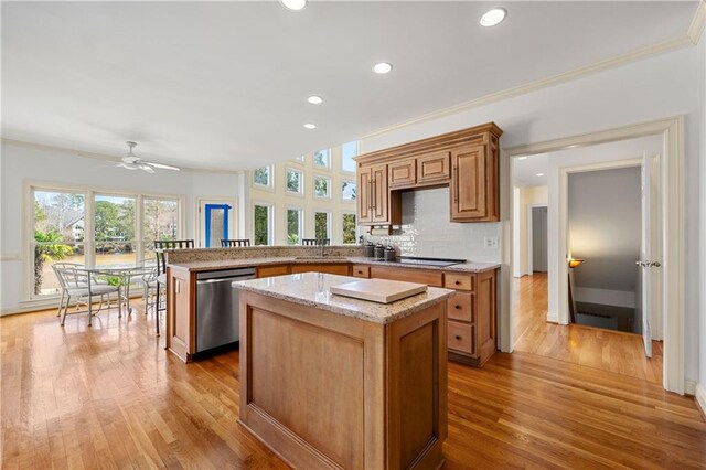 kitchen with a center island, backsplash, stainless steel dishwasher, light wood-type flooring, and a peninsula