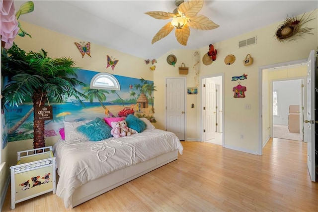 bedroom with light wood finished floors, visible vents, baseboards, ceiling fan, and vaulted ceiling