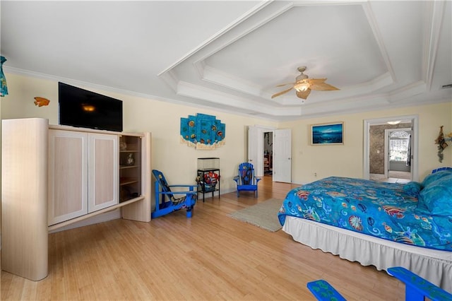 bedroom with crown molding, a ceiling fan, a raised ceiling, and wood finished floors