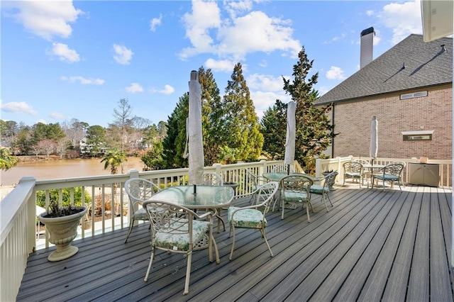 wooden terrace featuring outdoor dining space and a water view