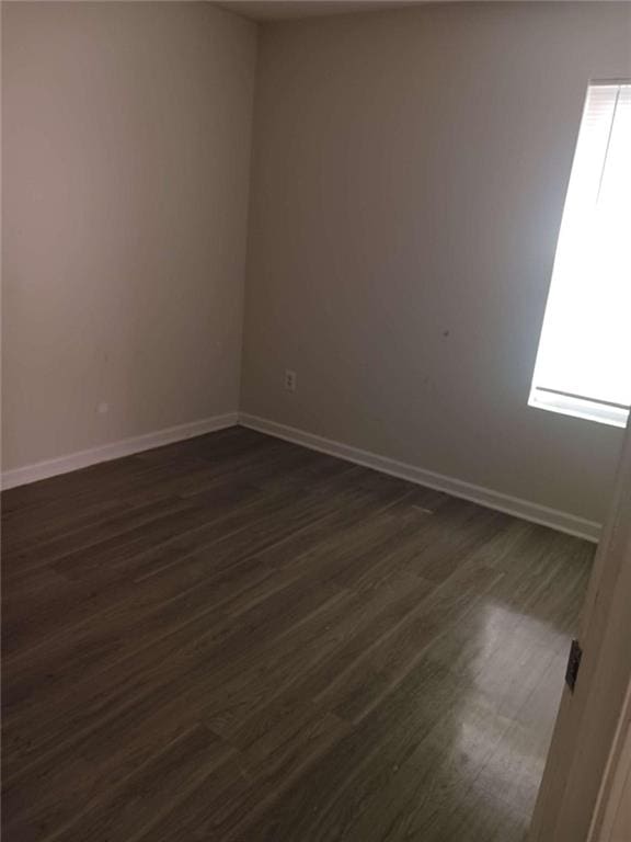 unfurnished room featuring a healthy amount of sunlight and dark wood-type flooring