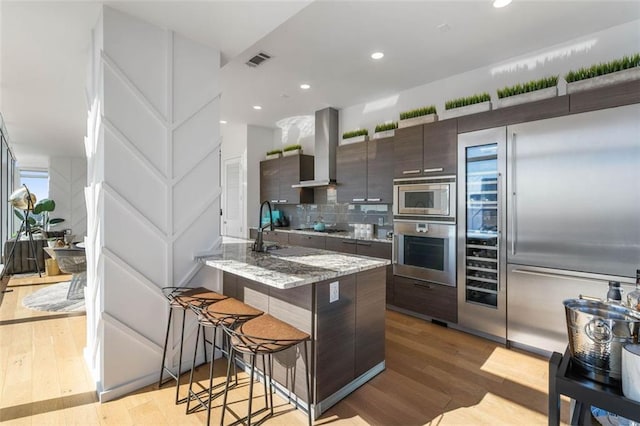 45 Ivan Allen Jr Blvd NW Unit 2505, Atlanta, GA 30308 - kitchen featuring built in appliances, island range hood, a breakfast bar, modern cabinets, and light wood-style flooring