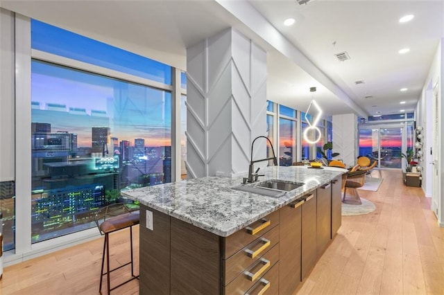 45 Ivan Allen Jr Blvd NW Unit 2505, Atlanta, GA 30308 - kitchen featuring a sink, modern cabinets, a kitchen island with sink, light wood-style flooring, and light stone counters