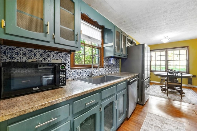 kitchen featuring green cabinets, a sink, stainless steel appliances, plenty of natural light, and a textured ceiling